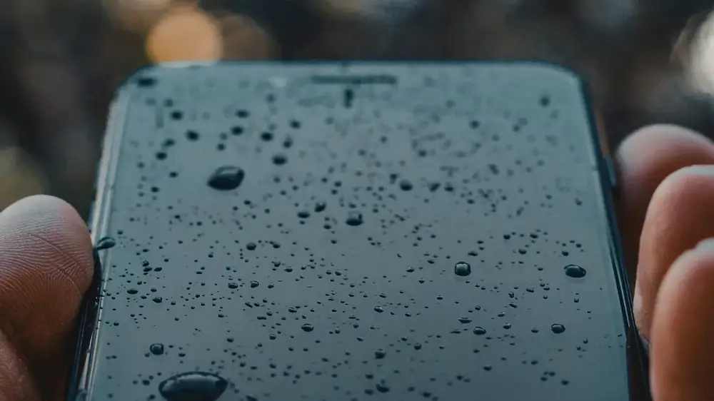 Üzerinde su damlaları olan siyah bir telefon